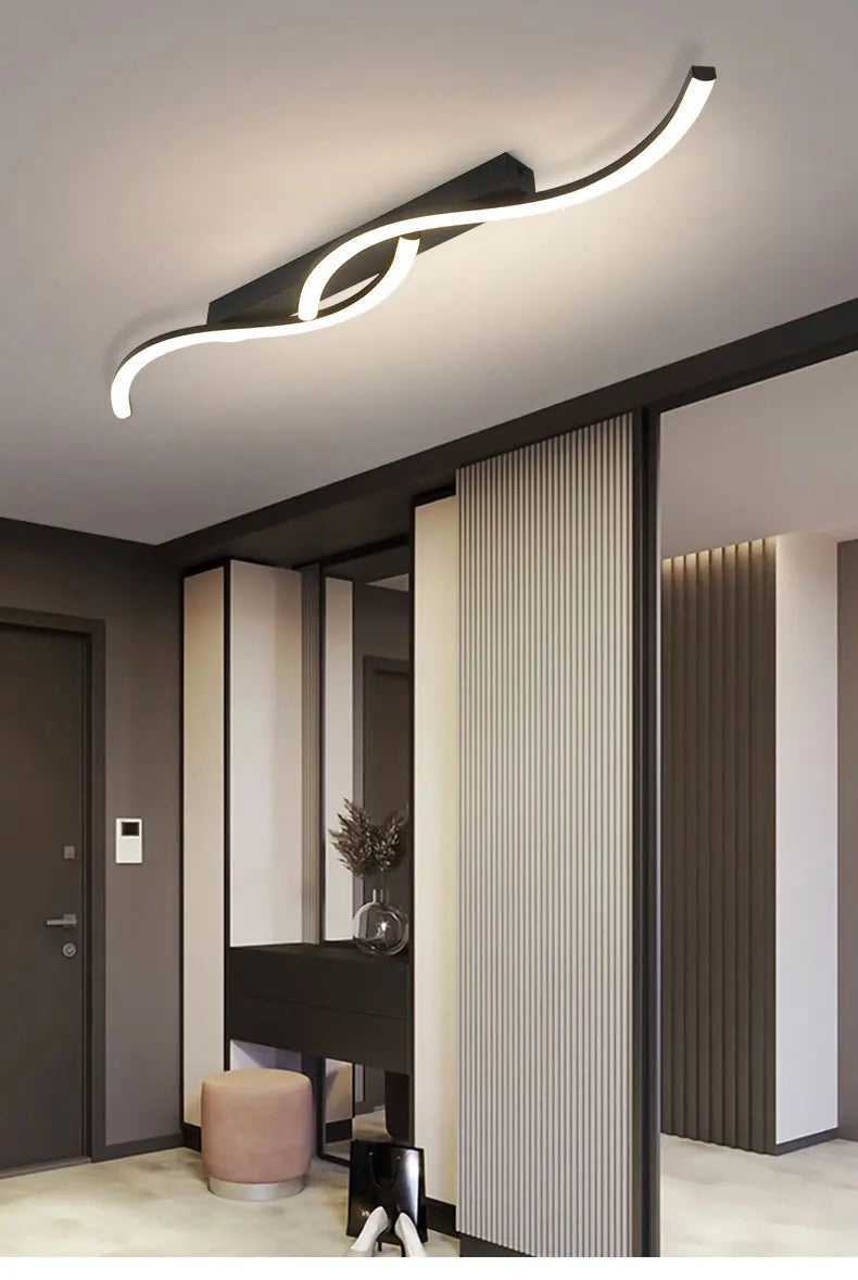 Plafonnier LED ondulé éclairant un couloir moderne.