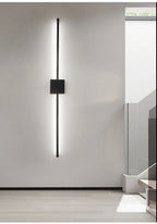Ambiance minimaliste avec applique murale LED linéaire noire sur mur blanc.